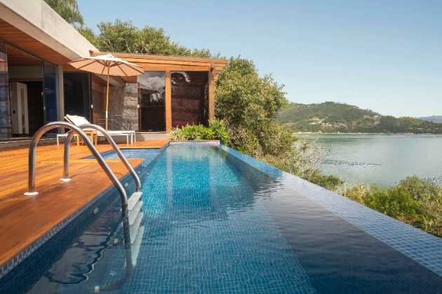 infinity pool overlooking body of water and mountains