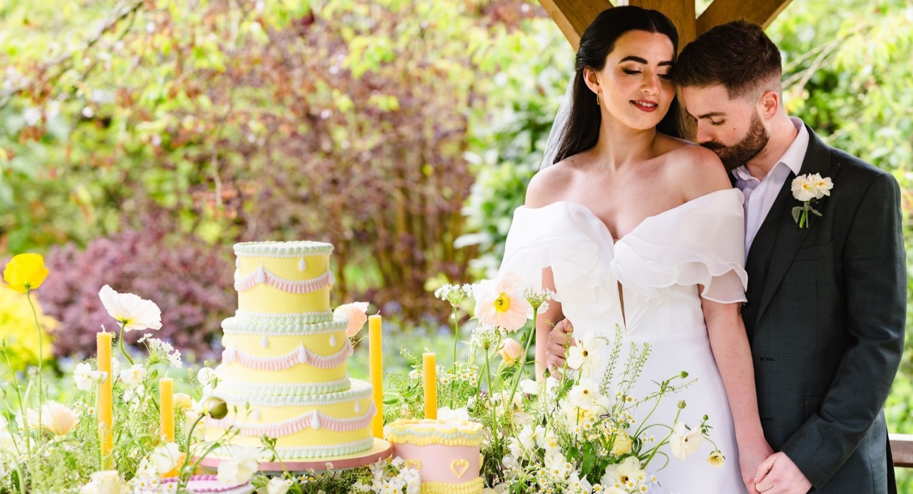 Bride and groom at Barnsdale Gardens with pastel coloured wedding cake and candles